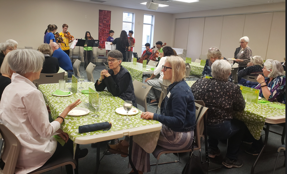 Overview of event - volunteers at tables and Orkidstra playing