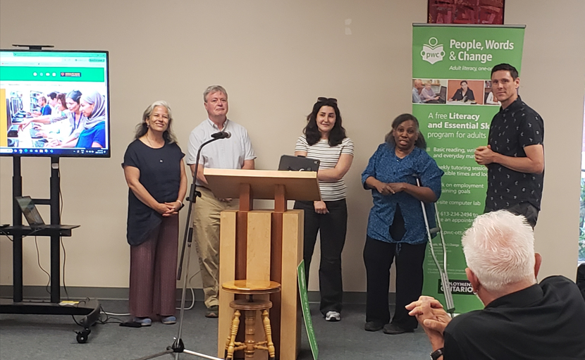 photo of the 3 learners who were in the new video standing at the front beside the tv that shows our new website. They are standing with 2 members from Character Creative, the company that did the website and video.